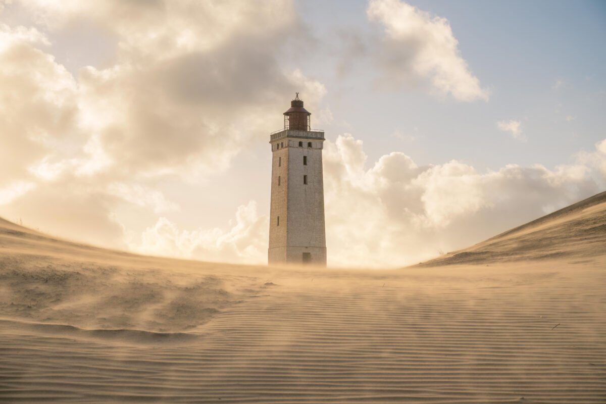 Rubjerg Knude lighthouse in blowing sand with dramatic sky