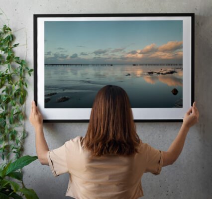 woman hanging fine art print in living room