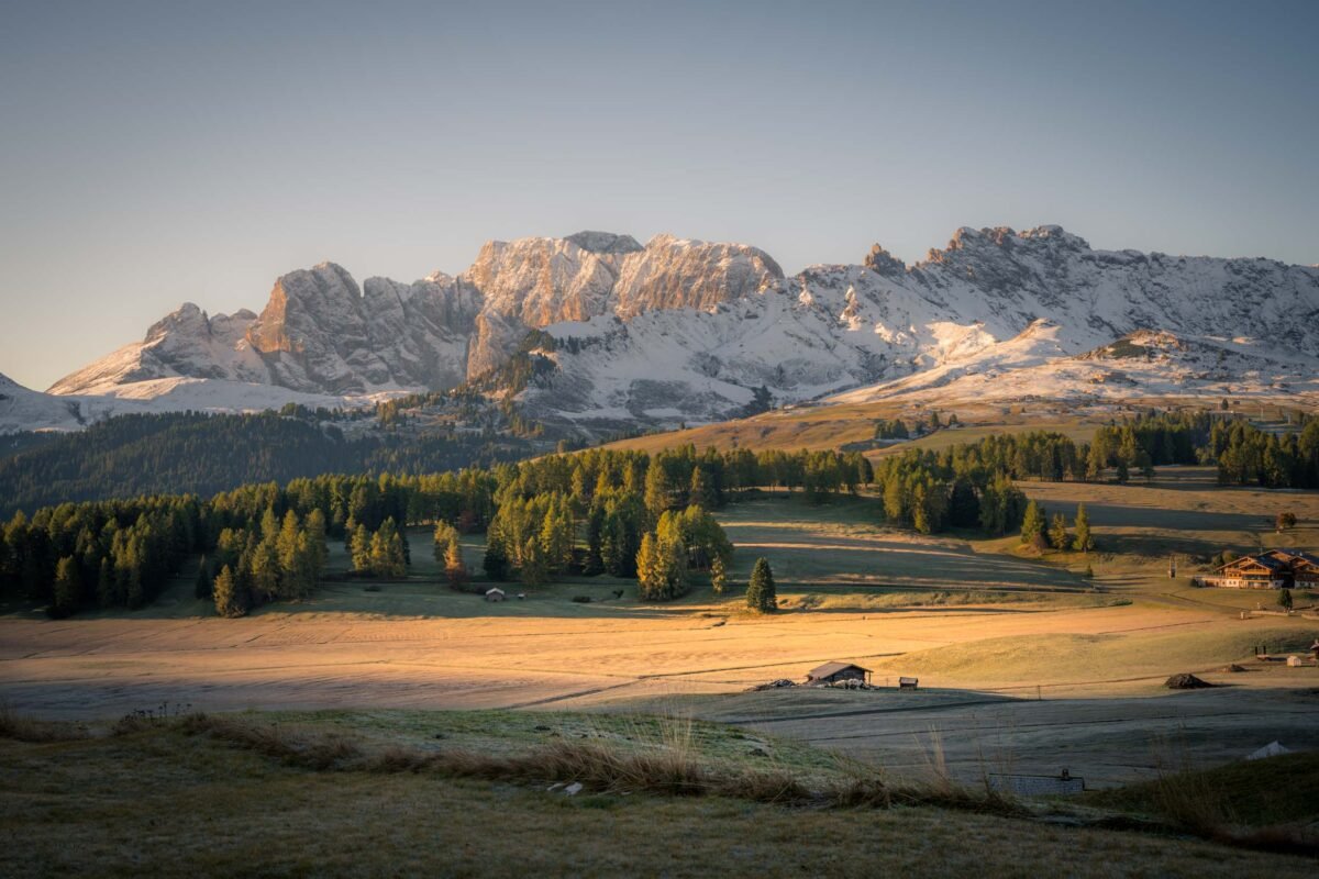 Seiser Alm at sunrise with morning mist over the alpine meadows and Sassolungo in the background