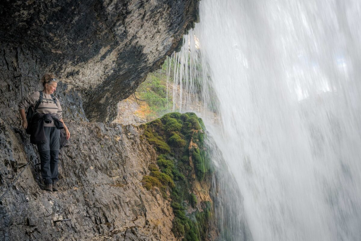 View from behind the waterfall with water cascading down the rocks
