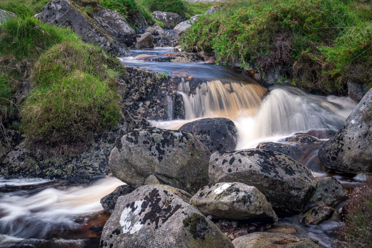 Glenealo-beek stroomt over met korstmos bedekte rotsen met lange sluitertijd gefotografeerd