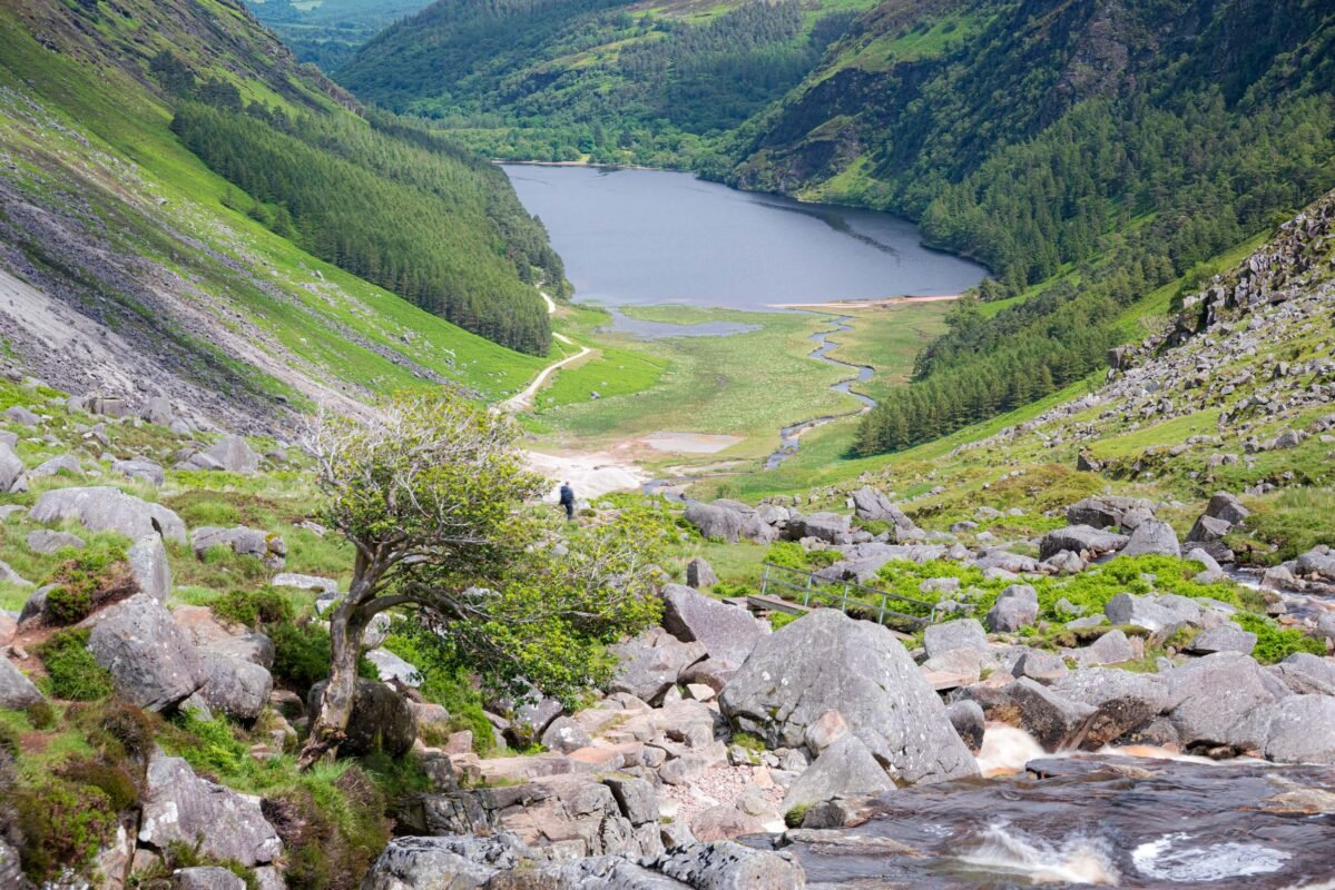 Uitzicht vanaf de Spinc over de Glenealo Valley met Upper Lake en wandelaar op het rotsachtige pad